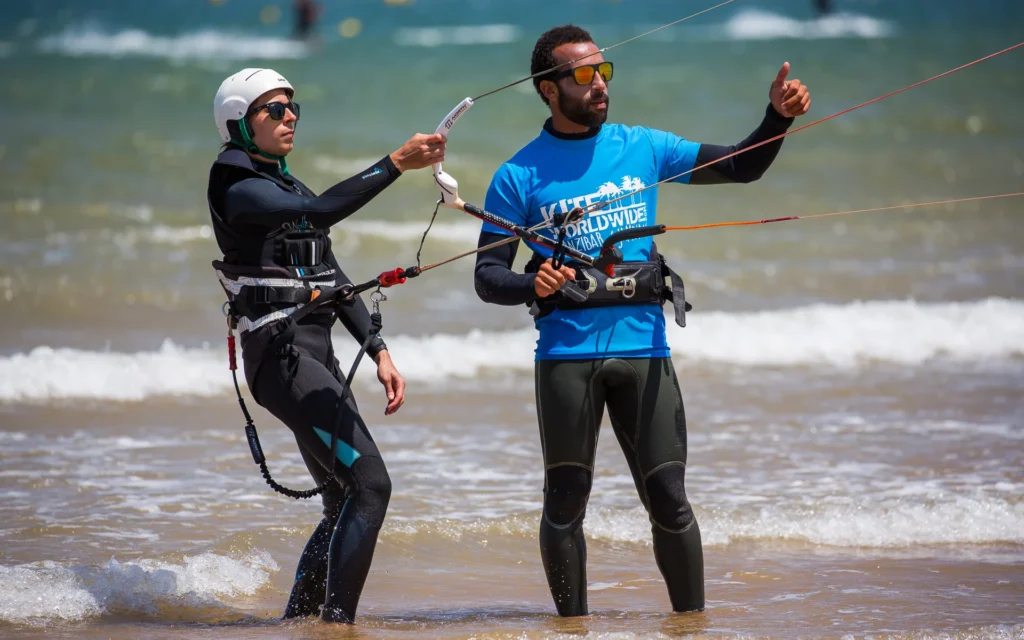 Kitesurf instructor guiding a student on the beach with a kiteboard in Essaouira, Morocco
