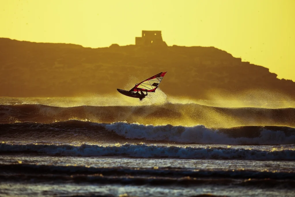 Windsurfer catching a wave at sunset in Essaouira, Morocco with Mogador Island in the background