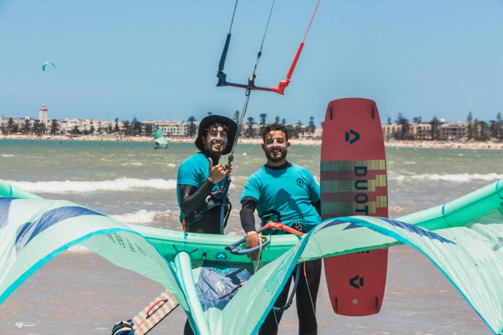 Two smiling kitesurf instructors posing on the beach in Essaouira with kite and board equipment
